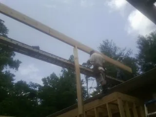 Carpenter setting a ridge beam over a new addition frame — Ice Dam Removal by Roofing Brothers in Raynham