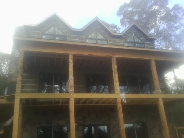 Dormers and porch framing on a large log home under construction — Roof Coating work by our crew in Raynham