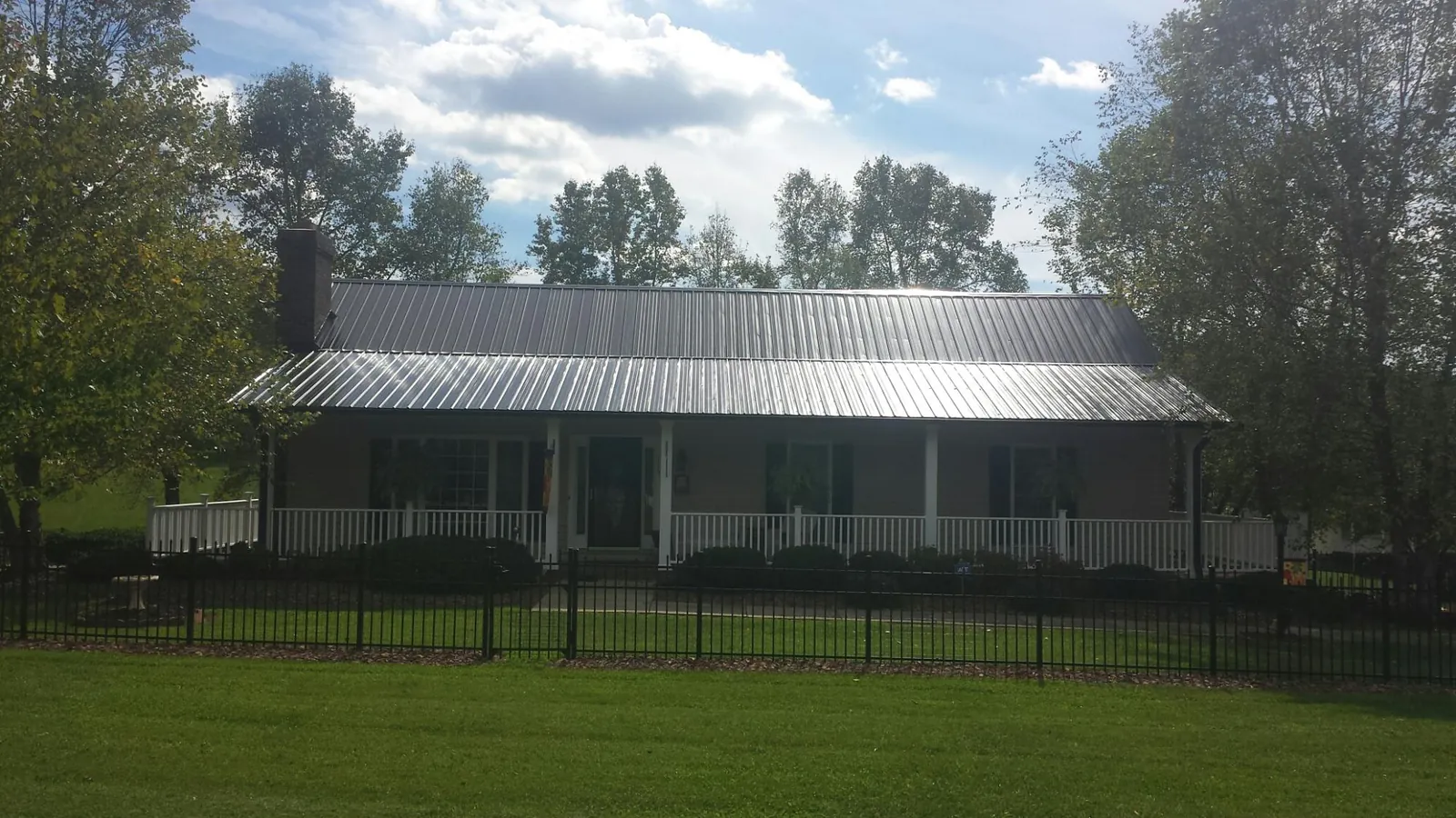 Gray metal roof on a brick ranch with a full width front porch — Gutter Guard Installation work by our crew in Raynham