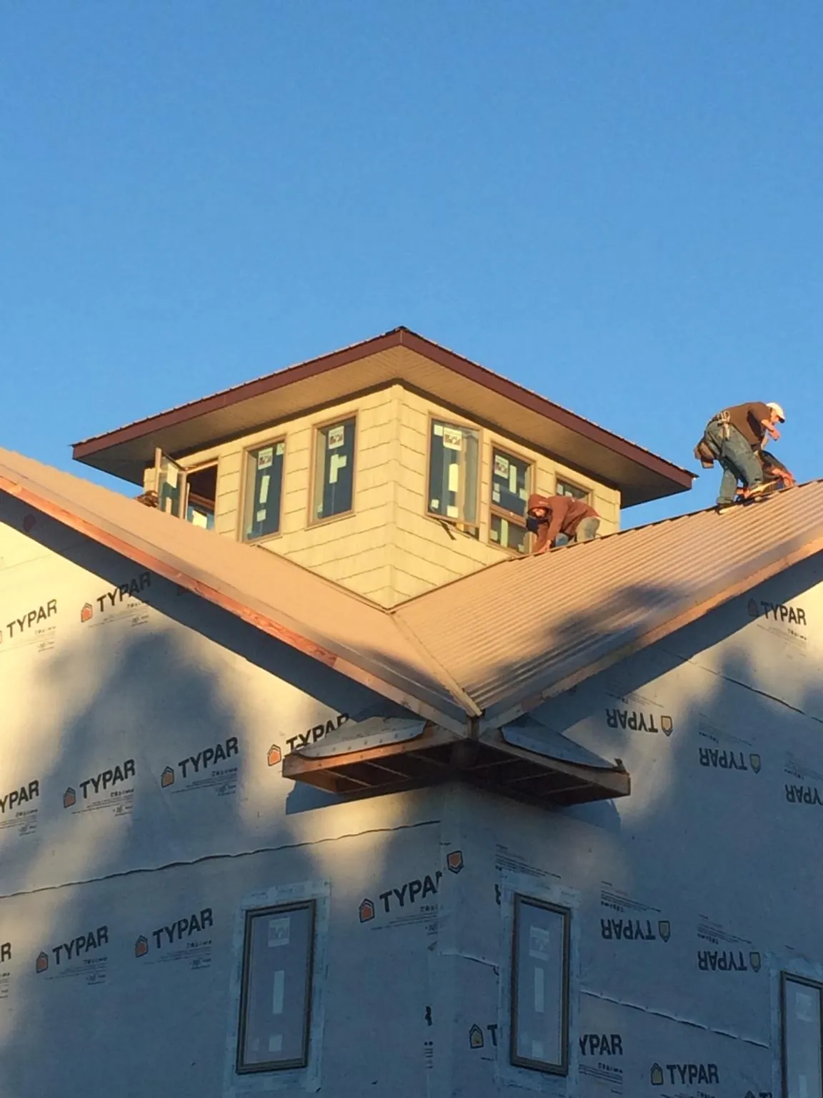 Roofers working around a rooftop cupola on a new metal roof at sunset — Roof Waterproofing in Raynham by Roofing Brothers